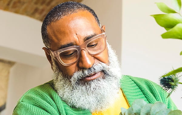 Relaxed gentleman who is mindfully tending to his indoor plants in his home environment.